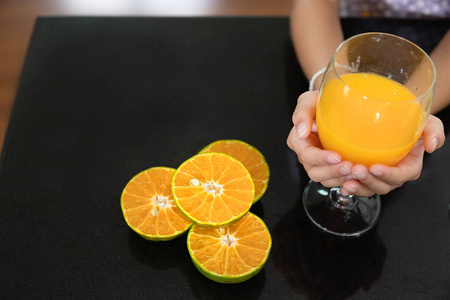 小女孩手里拿着一杯橙汁在厨房里