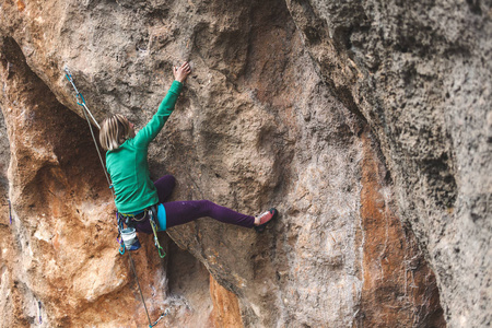 一个女人爬上岩石。攀登自然。户外健身。积极的生活方式。极限运动。运动员在自然的救援中训练