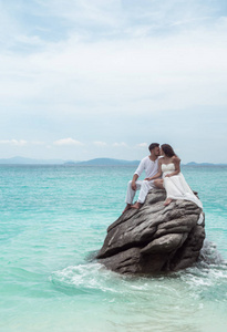 迷人的年轻夫妇在热带岛上。美丽的女人和男人穿着白色的衣服拥抱对方, 享受 trpoical 假期假期度假