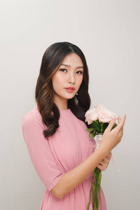 一个满意的年轻女子的肖像, 身着粉红色的礼服持有玫瑰花花束隔离在白色背景