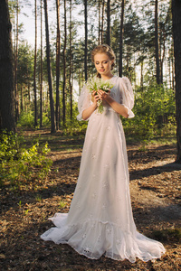 在森林和享受自然的复古白色礼服的愉快的妇女