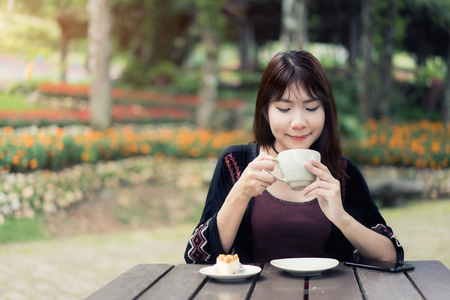 亚洲妇女在自家花园里放松身心, 喝杯咖啡, 感受清新
