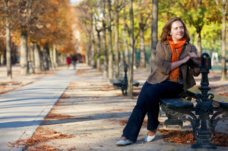 美丽的姑娘坐在长椅上在巴黎秋天
