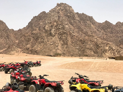 大转弯是一个串的许多四轮多彩多姿的强大快速越野四轮驱动 Atvs 在沙质炎热的沙漠在停车场的背景下高山