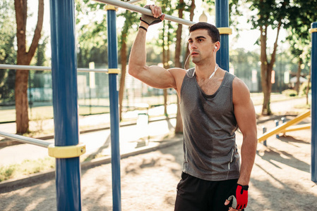 运动后的男子在水平酒吧运动, 户外健身锻炼。健美运动员在公园运动训练中的研究