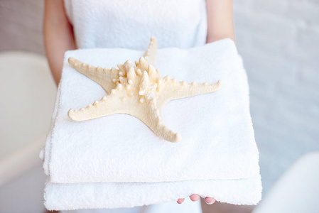 特写女子手持白色浴巾装饰着海星。水疗酒店度假胜地的概念