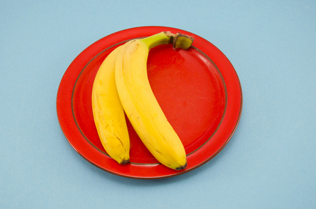 两个黄色的香蕉在红板