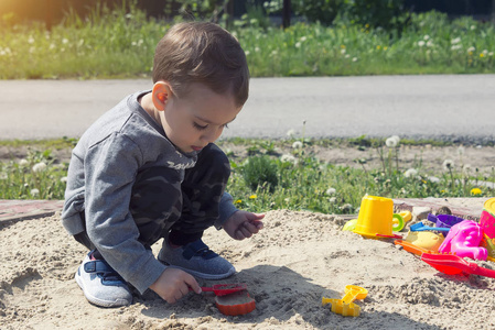 小男孩在沙滩上玩耍, 孩子在阳光明媚的天气里玩着操场上的公园。