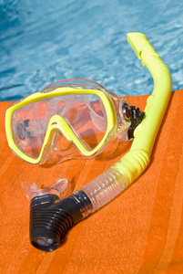 上一条毛巾在游泳池旁边的黄色浮潜