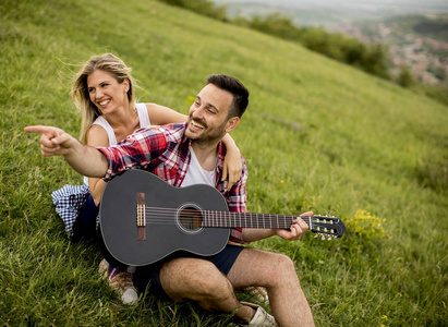 爱的人坐在草地上与他的女朋友和弹吉他