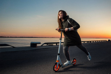快乐的女人骑着一只脚踏滑板车