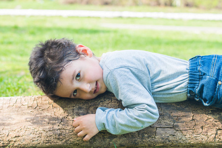 4岁的黑发男孩躺在原木上
