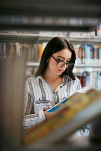 学生妇女在书店或图书馆搜索书籍。在书架上寻找课本的女人。高分辨率