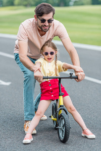 快乐的父亲教小女儿骑自行车