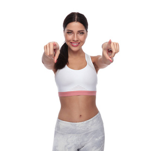 美丽的健身女人的肖像站在白色背景上指着手指