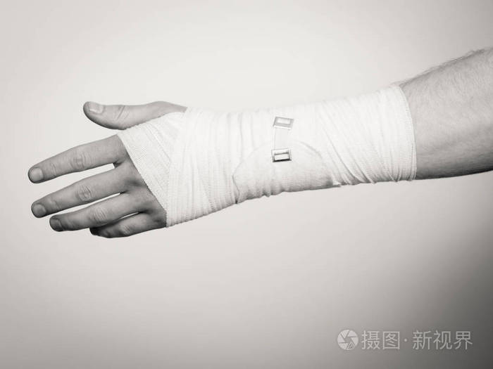 在白色绷带的男性手.乐于助人的药物治疗痛苦棕榈手臂的年轻人