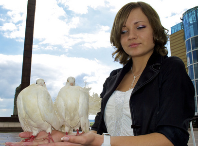 可爱的俄罗斯女孩在她的手中保存两个白色的鸽子