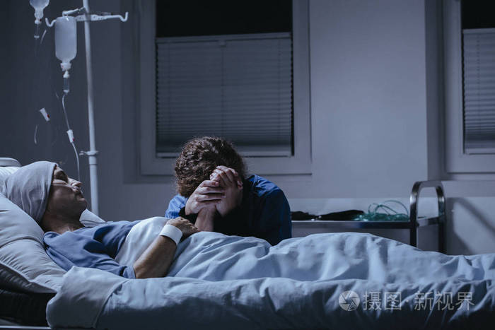 女儿在医院里垂死的母亲的床上哭泣.乳癌概念