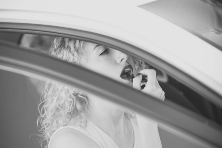 妇女或女孩在汽车唇上涂抹红唇膏