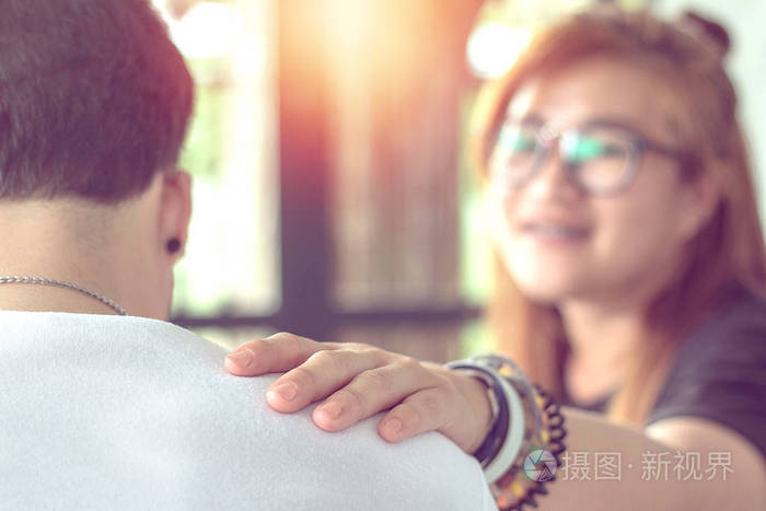 年轻的亚洲妇女手抚摸着年轻人的肩膀安慰她的男朋友