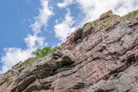 攀岩。一个年轻的登山者爬上垂直的花岗岩岩石。极限运动