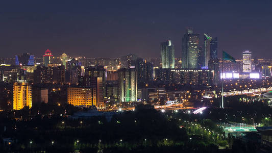 上升的夜视图在市中心和中央商业区与 bayterek 和旗子时差照亮打开了, 卡扎克斯坦, 阿斯塔纳, 中亚