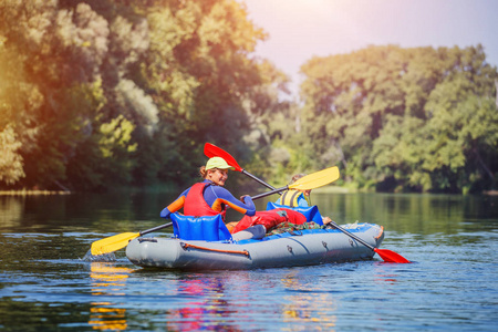 快乐的女孩独木舟在河上的阳光明媚的一天在暑假里