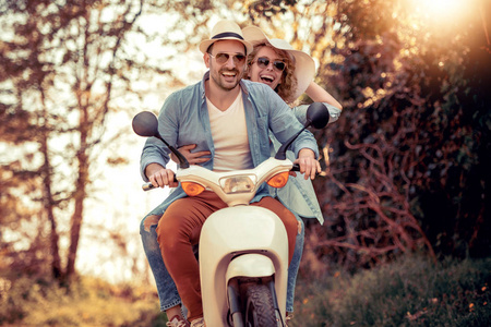 快乐的年轻夫妇，在晴朗的一天骑摩托车在城市