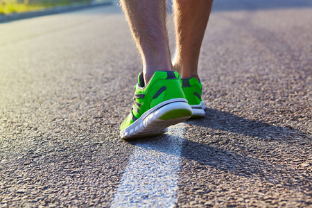 赛跑者脚跑在路特写在鞋子。男性健身运动员慢跑运动的健康概念。男运动员在跑鞋。慢 跑