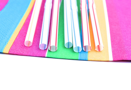 五颜六色的餐巾上的彩色吸管。塑料和纸