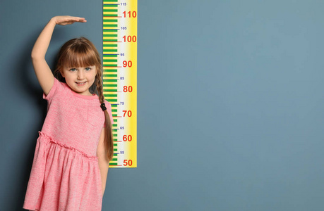 小女孩在颜色背景测量她的高度
