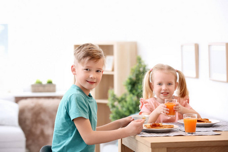 可爱的小孩子吃可口的烤面包与果酱在桌上
