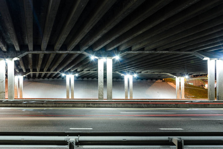 混凝土道路桥梁结构的底部视图。公路交汇处的夜间交通灯径