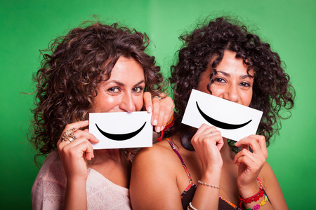 两个年轻妇女与绿色背景上的笑脸图释