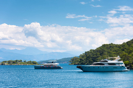 两艘现代游艇在风景如画的海湾。背景中的岛屿和山脉。在海上度过的暑假