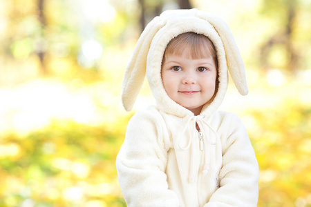 漂亮的小女孩在服装小兔子在秋天的森林中