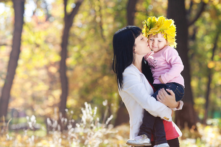 美丽年轻的母亲，她的女儿举行的枫叶花圈