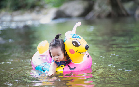 小女孩与粉红色橡胶圆环在自然水在假日