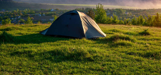 日出时草坪上的旅游帐篷