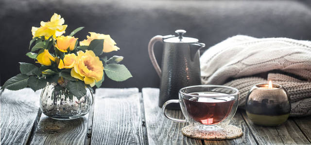 一杯茶, 茶壶和玫瑰花在花瓶里, 站在家里的客厅里的木桌上。