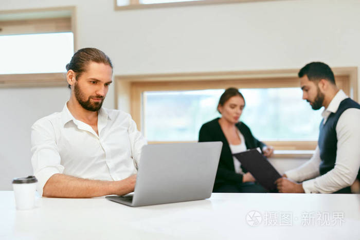 做生意的人在电脑上工作.在现代办公室里, 男工人在笔记本电脑上工作.