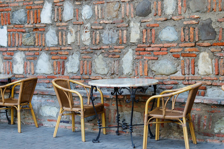户外咖啡馆的桌椅。庭院设置反对石墙壁