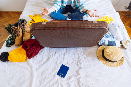 床上有冬夏衣服的手提箱。准备旅行。带衣服的手提箱。旅游理念