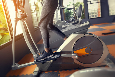 年轻女孩锻炼自行车健身运动的妇女减肥与机器有氧为苗条和坚定的运动员建设者肌肉生活方式