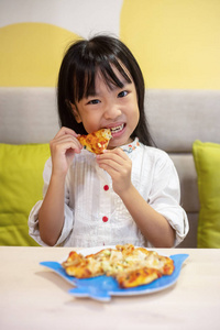 亚洲小中国女孩在餐馆吃比萨饼