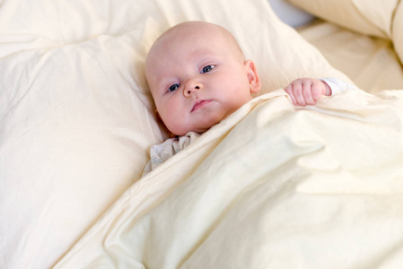 小男孩躺在他父母的床上枕头下的毯子