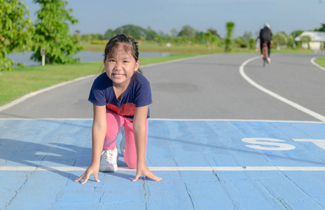 微笑可爱的女孩在准备好的位置跑在轨道, 体育和健康概念