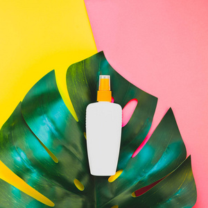 热带丛林棕榈龟背竹叶子和防晒霜空白瓶样机在明亮的正方形黄色和粉红色双色调纸背景。暑期创意平面布局概念模板文本