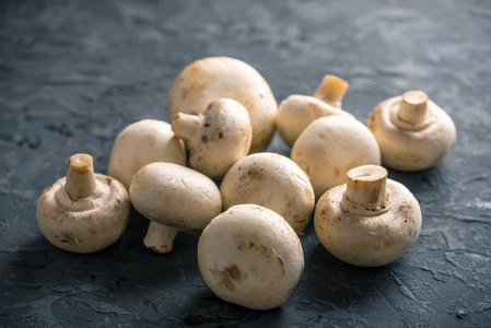 新鲜的白色 champignons 在黑暗的厨房桌子上。用蘑菇烹调美味的菜肴