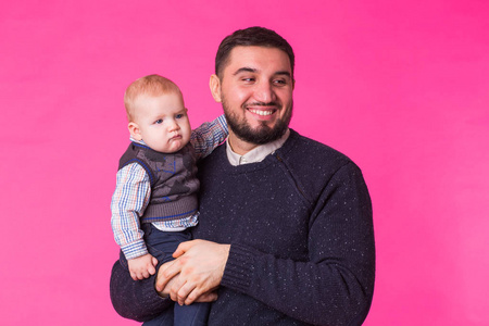 幸福的父亲与一个男婴孤立在粉红色的背景